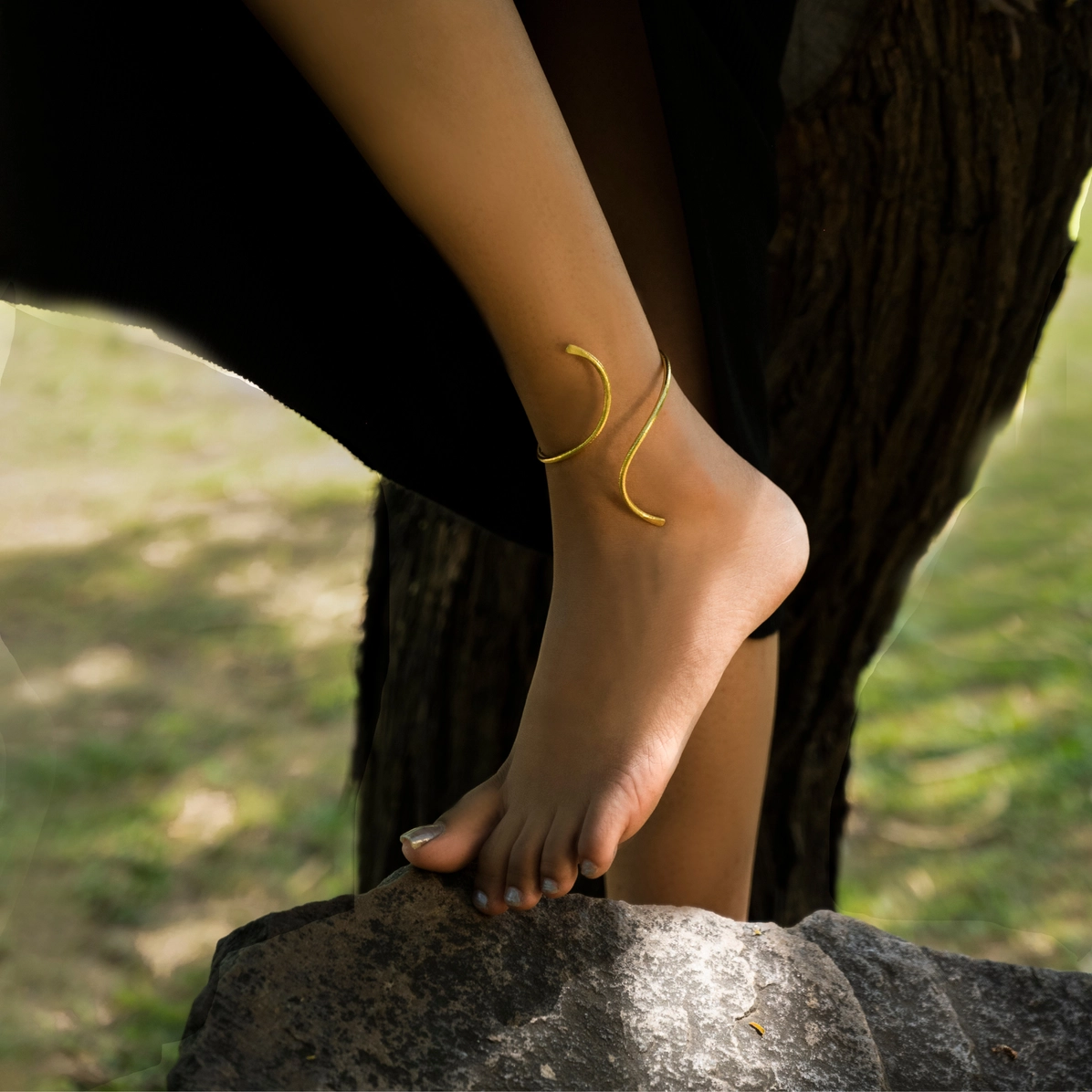 18K gold‑plated brass minimalist ankle cuff with smooth sculptural design on a woman's ankle,
