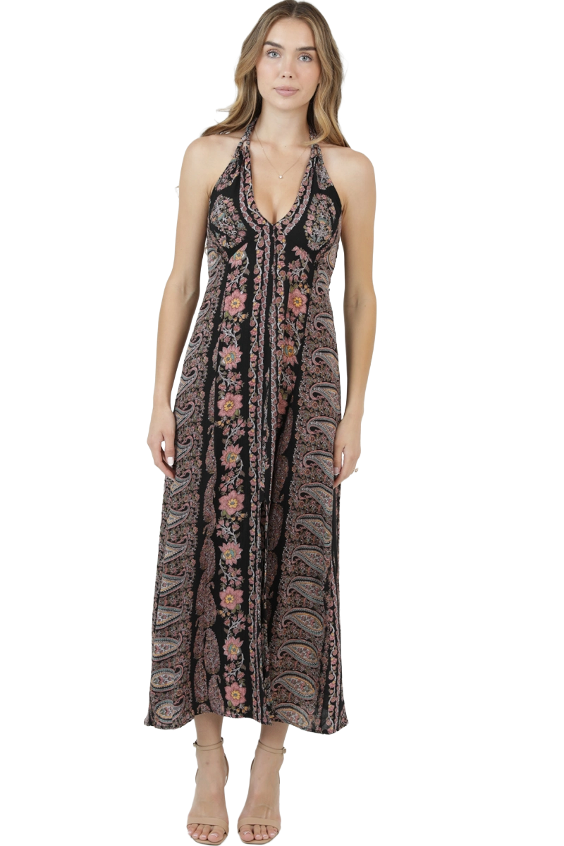 Woman wearing a printed halter neck paisley maxi dress with a center slit in black and pink tones.